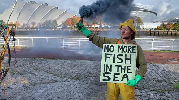 Man holding a sign that says No more fish in the sea